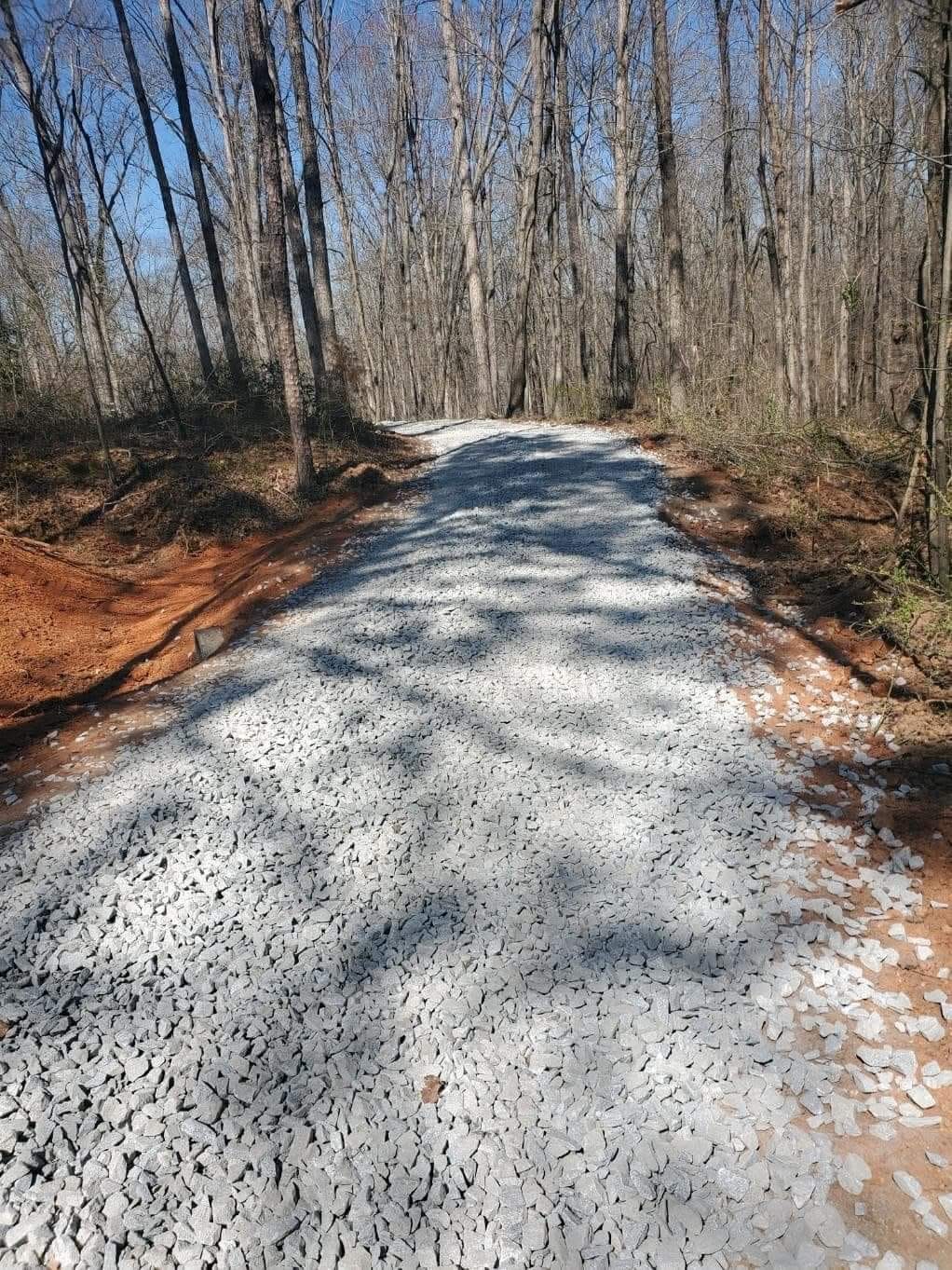 Completed gravel access road winding through woods